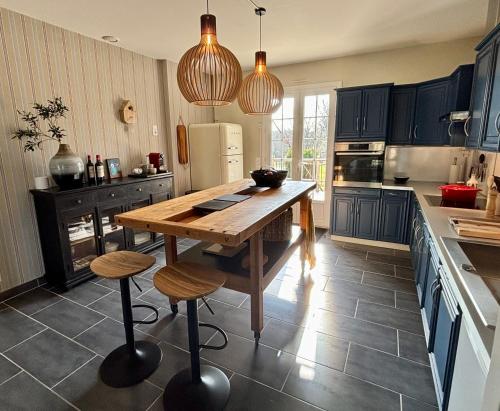 une cuisine avec une table en bois et deux tabourets dans l'établissement Gite Le Petit Wren - avec piscine et vue, à Fumel