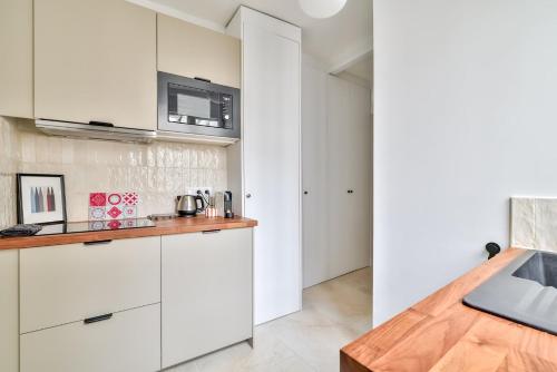 une cuisine avec des armoires blanches et un évier dans l'établissement Paris à Pied : Folies Bergère et Grands Boulevards, à Paris