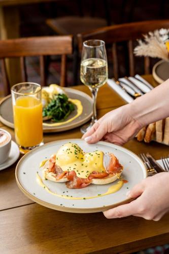 a person holding a plate of food on a table at The Olde Coach House Inn in Ashby Saint Ledgers