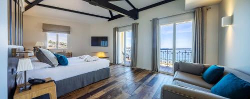a bedroom with a large bed and a couch at Hôtel de la Plage - Saint Jean de Luz in Saint-Jean-de-Luz