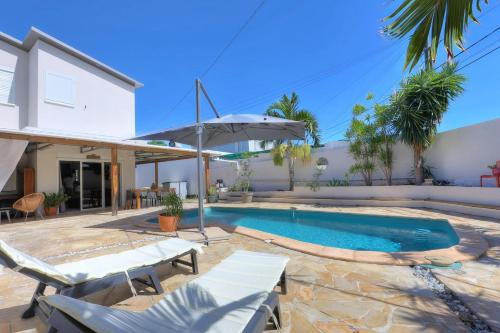 a swimming pool with two chairs and an umbrella at La Villa M&M - entre Mer et Montagne - La Possession in La Possession