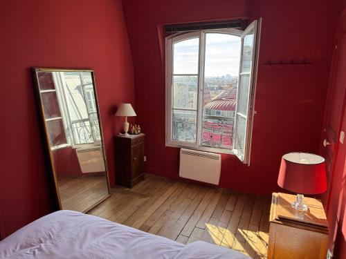 Cette chambre rouge comprend un miroir et une fenêtre. dans l'établissement Quiet & Bright Apartment, à Paris