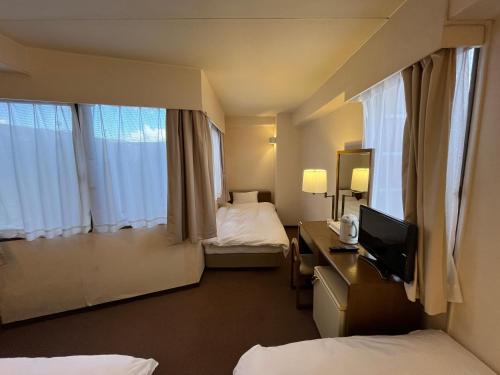 a hotel room with two beds and a desk with a television at リオンドール in Kyoto