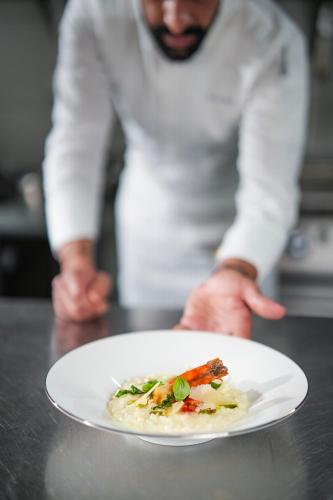 a man holding a plate of food on a table at The Biltmore Hotel Villas, Dubai in Dubai