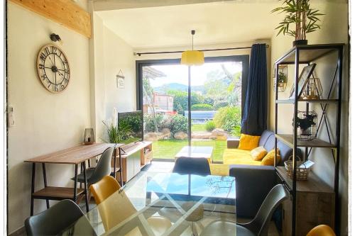 - un salon avec une table, des chaises et une horloge dans l'établissement Villa DOLCE, piscine privée chauffée & jacuzzi privatif, 5mn des plages, à Porto-Vecchio