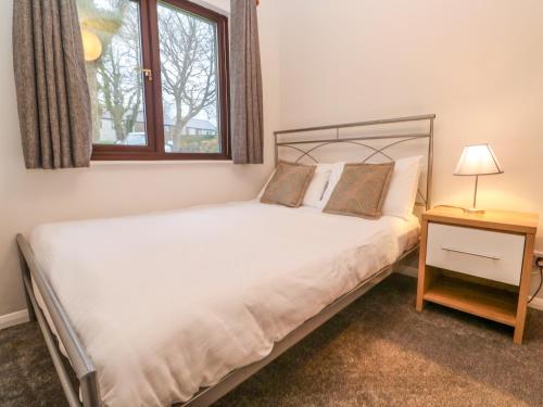 un dormitorio con una cama y una ventana en Mousehole Bungalow, en Penzance