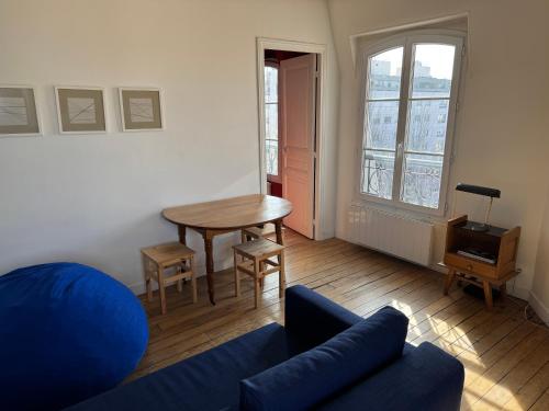 un salon avec un canapé bleu et une table dans l'établissement Quiet & Bright Apartment, à Paris