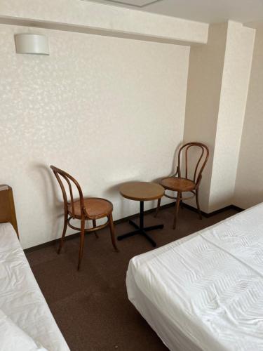two chairs and a table and two beds in a room at リオンドール in Kyoto