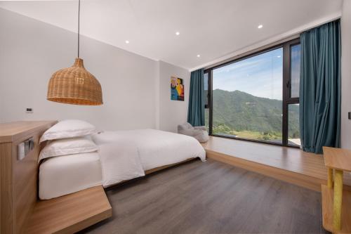 a bedroom with a bed and a large window at Healing House--Free one way pick up service over 2 nights in Zhangjiajie
