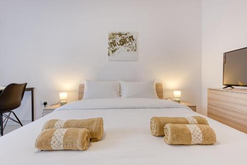 una camera da letto con un letto bianco e una tv di New Studio in Msida a Msida