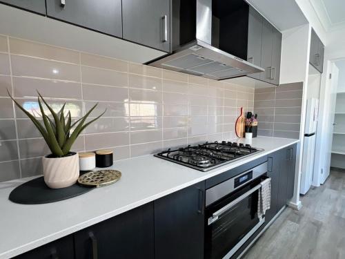 a kitchen with a stove and a counter top at KozyGuru Pakenham Comfortable 4-Bedroom House in Pakenham