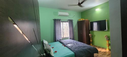a bedroom with green walls and a bed and a window at Home away from Home for families in Ayodhya