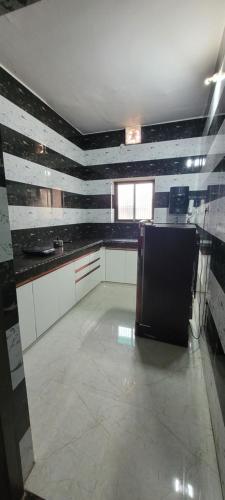 a kitchen with black and white walls and a refrigerator at Home away from Home for families in Ayodhya