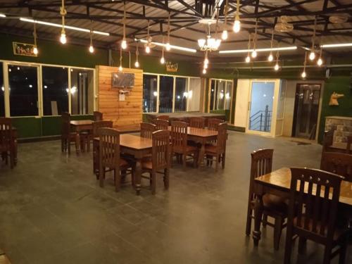 a dining room with wooden tables and chairs and lights at LA Riqueza Pride Inn # Rootop Swimming Pool with Mountain View # Free Parking # Tapovan # Center of Rishikesh# in Rishīkesh