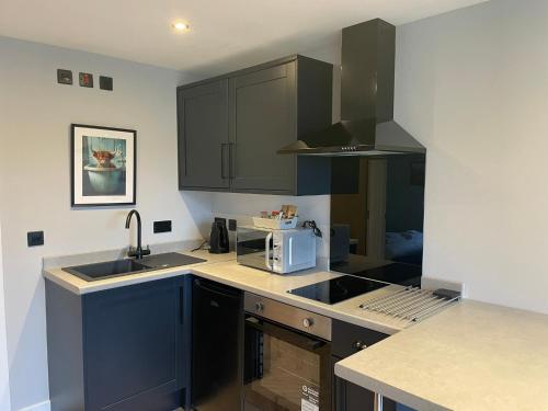 a kitchen with black cabinets and a sink and a microwave at River Logie Lodges in Westfield