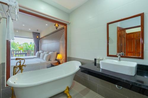a bathroom with a tub and a bed and a sink at Herbal Resort & Spa in Phu Quoc