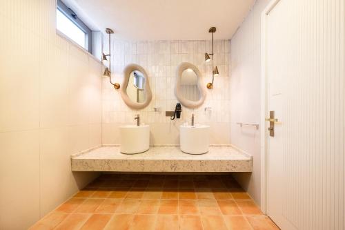 two sinks in a bathroom with two mirrors at Dione Bozcaada in Bozcaada