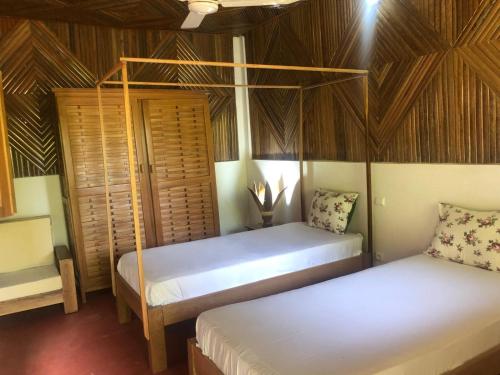 two beds in a room with wooden ceilings at STYLE MALGACHE et TOUT CONFORT in Nosy Be