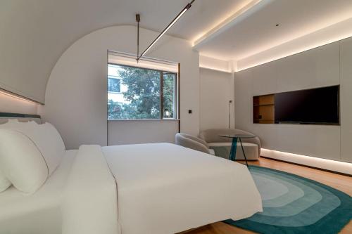 広州市にあるYee Hotelのベッドルーム(白い大型ベッド1台、薄型テレビ付)