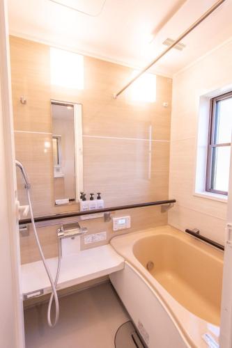 a bathroom with a tub and a sink and a mirror at hasunumacottageA in Hasunuma