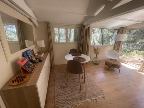 un salon avec une table, des chaises et des fenêtres dans l'établissement Le Charmeur - Le Chalet Attrape-Coeur, à Aix-en-Provence