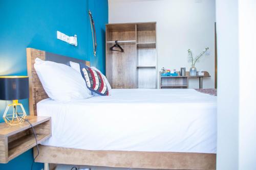 a bedroom with a bed and a blue wall at Mémorial Hôtel in Ouagadougou