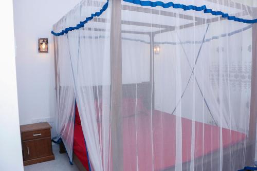 a bedroom with a canopy bed with curtains at Garden Villa in Midigama