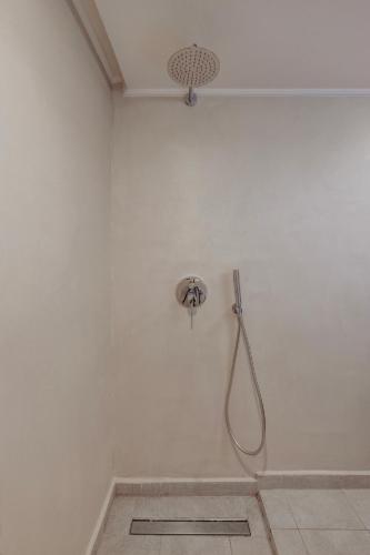 a shower in a white bathroom with a shower head at Noema Lindos - Athena Apartment in Líndos