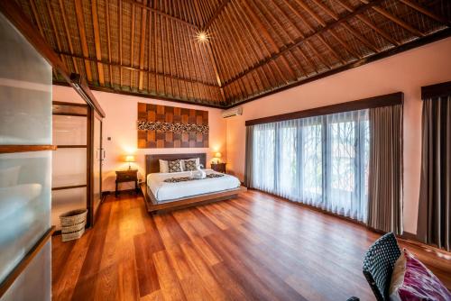 a bedroom with a bed and a large window at The Kampung Ubud Villa in Ubud