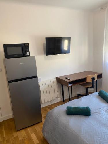 Cette chambre comprend un lit, un bureau et un réfrigérateur. dans l'établissement Studio meublé CIRCUIT 24h, au Mans