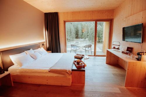 a bedroom with a large bed and a balcony at Campra Alpine Lodge & Spa in Olivone