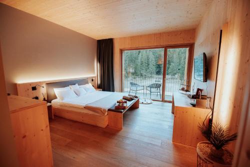 a bedroom with a bed and a large window at Campra Alpine Lodge & Spa in Olivone