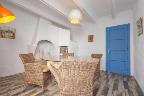 a dining room with a table and chairs and a blue door at Can Calpe in Can Picafort