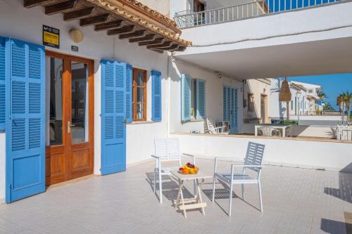 a patio with blue shutters and a table and chairs at Can Calpe in Can Picafort