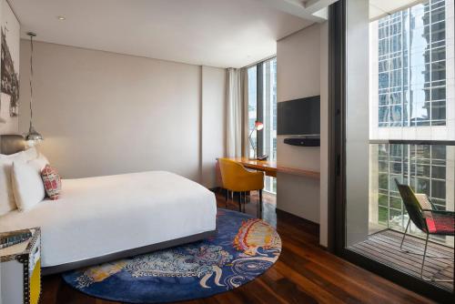 a hotel room with a bed and a desk and a window at Hotel Indigo Bangkok Wireless Road by IHG in Bangkok
