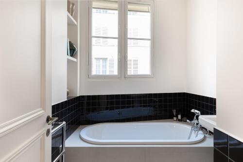 une baignoire dans une salle de bain avec une fenêtre dans l'établissement Pick A Flat's apartment in Saint-Germain - Place Furstemberg, à Paris