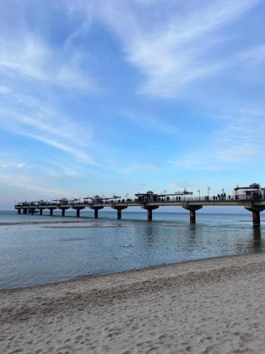 a pier on the beach with people walking on it at Apartament Morski Widok Międzyzdroje in Międzyzdroje