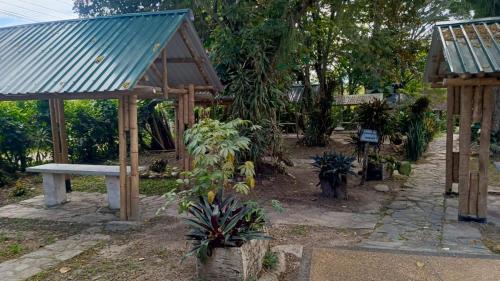 a park with a bench and some plants and trees at Hotel Hábitat Campestre "cerca al Parque deportivo" in Ibagué