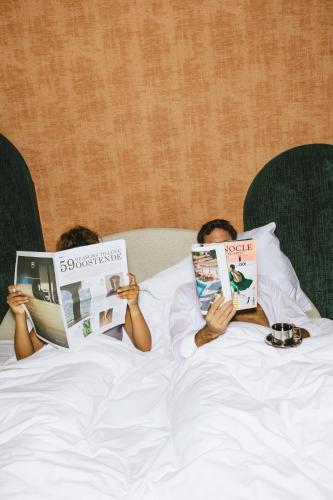 two people laying on a bed reading books at The Ostendian in Ostend