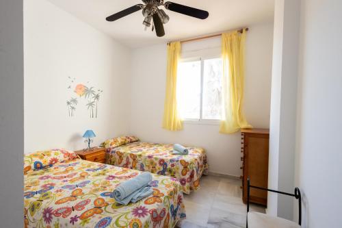 Un dormitorio con dos camas y una ventana. en Costa Ballena - Apt para 6 con piscina, terraza, WiFi y parking gratis, en Rota