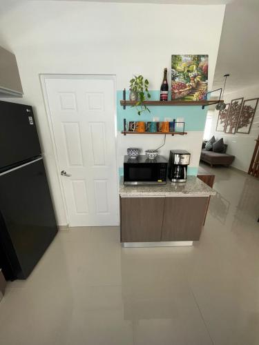 a kitchen with a counter with a microwave and a refrigerator at Casa de huéspedes a solo 10 minutos la Playa in Playa del Carmen