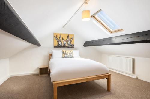 a bedroom with a white bed and a skylight at Rigg Farm Cottage - NR Whitby in Stainsacre