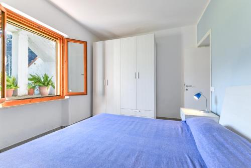 a bedroom with a blue bed and a window at Casa Gaia direttamente sul mare in Pomonte