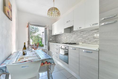 a kitchen with white cabinets and a table with chairs at Casa Gaia direttamente sul mare in Pomonte