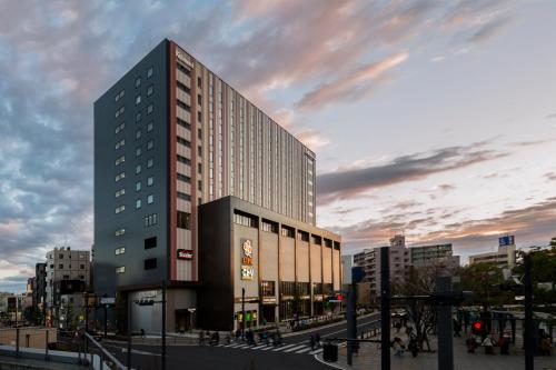 um edifício alto numa cidade com um céu nublado em Richmond Hotel Premier Tokyo Schole em Tóquio