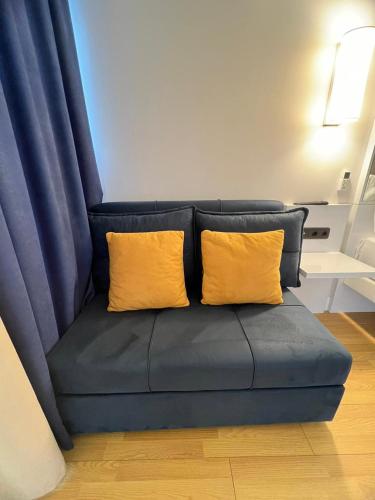 a blue couch with two yellow pillows on it at ORBI City N8 HoTeL in Batumi