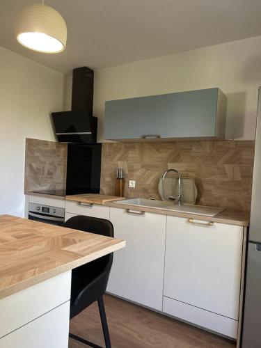 a kitchen with white cabinets and a wooden counter top at Jumapi house in Fontaine-le-Comte