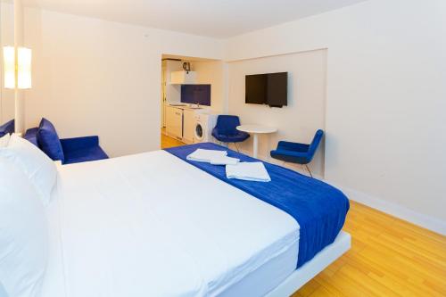 a bedroom with a large bed and two blue chairs at ORBI City N9 HoTeL in Batumi