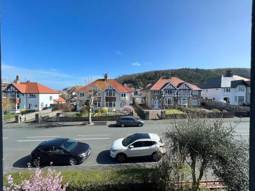 zwei Autos auf einem Parkplatz mit Häusern geparkt in der Unterkunft The 100 House - Llandudno in Llandudno
