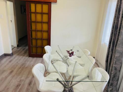 a room with a glass table and white chairs at House 210 holiday rentals in Alberton